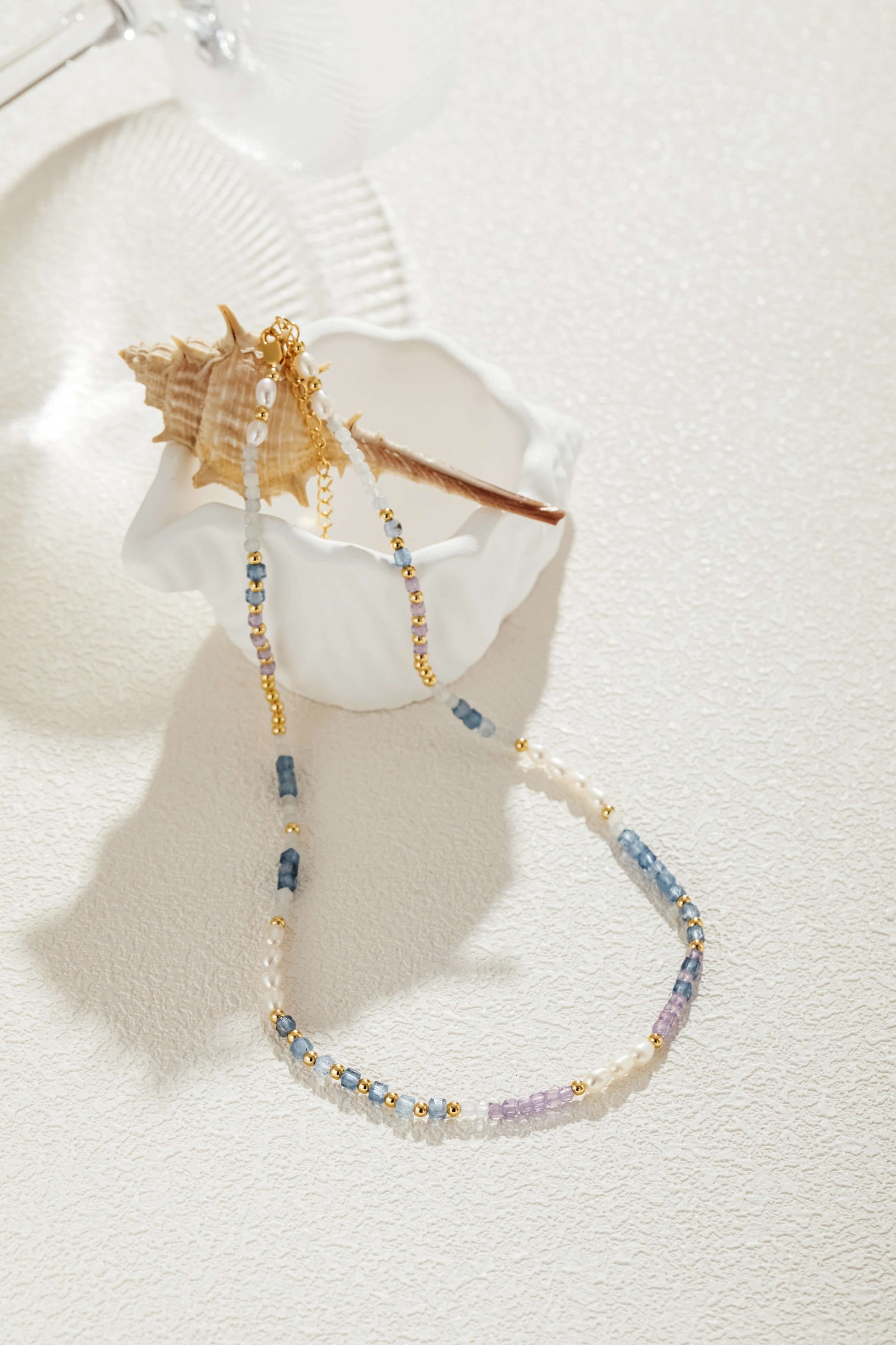 "Ocean" Natural Gemstone Necklace by SUIHE Jewelry with blue, lavender, and white stones, gold-plated beads, and freshwater pearls.
