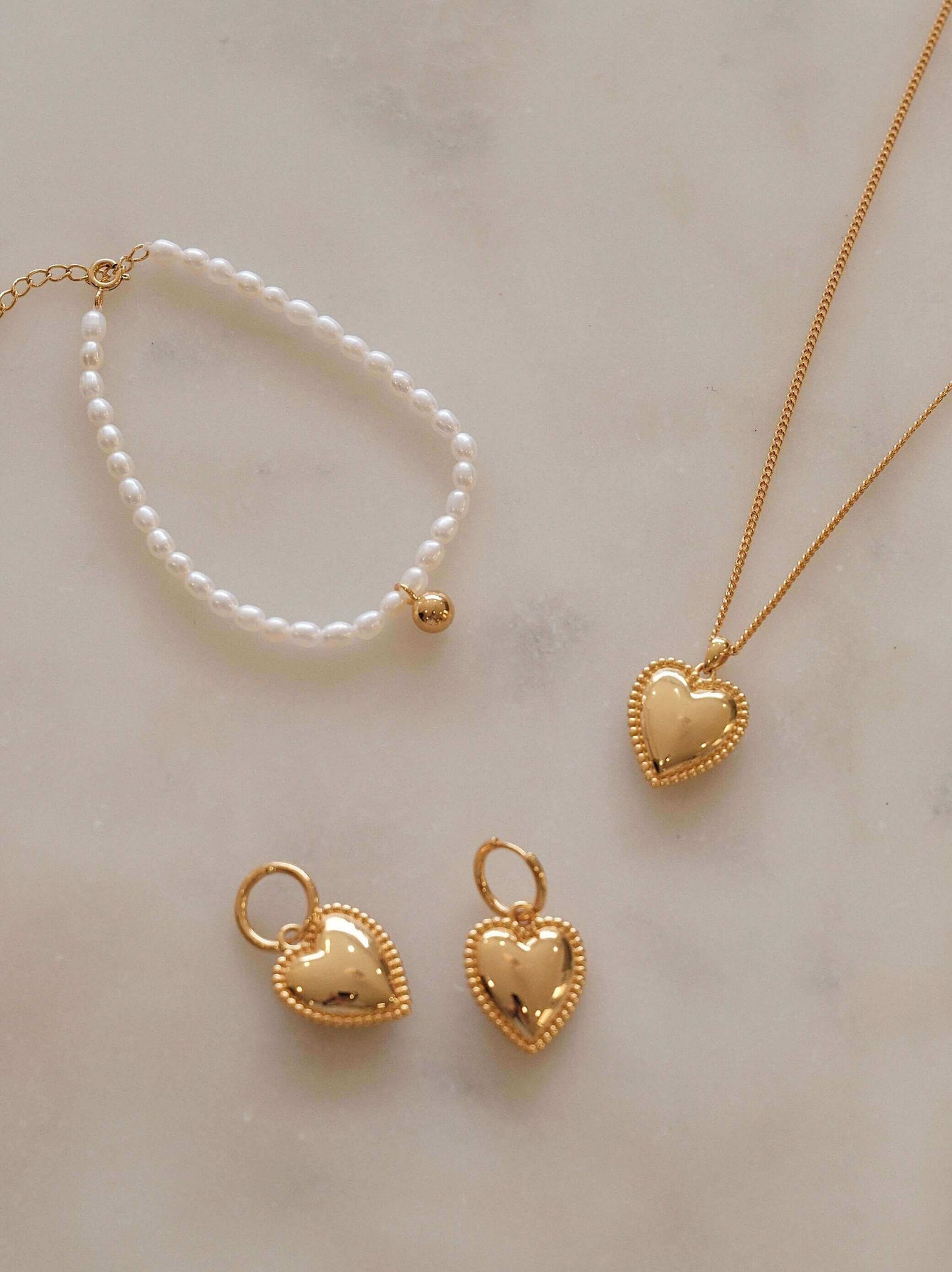 Celestia Freshwater Pearl Bracelet and gold heart jewelry set by SUIHE Jewelry on marble surface.