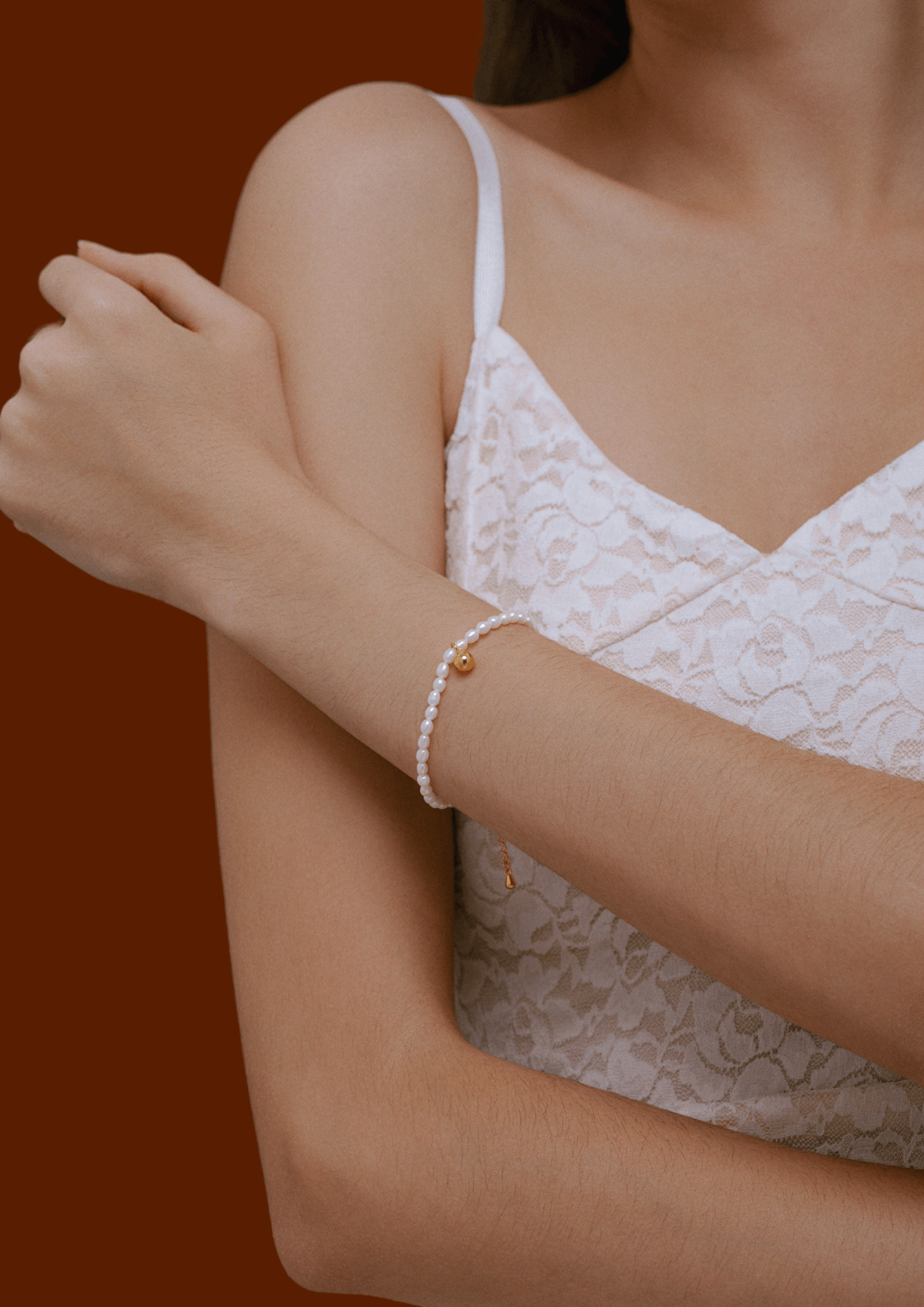Elegant woman wearing Celestia freshwater pearl bracelet with gold-tone bead by SUIHE Jewelry on her wrist.