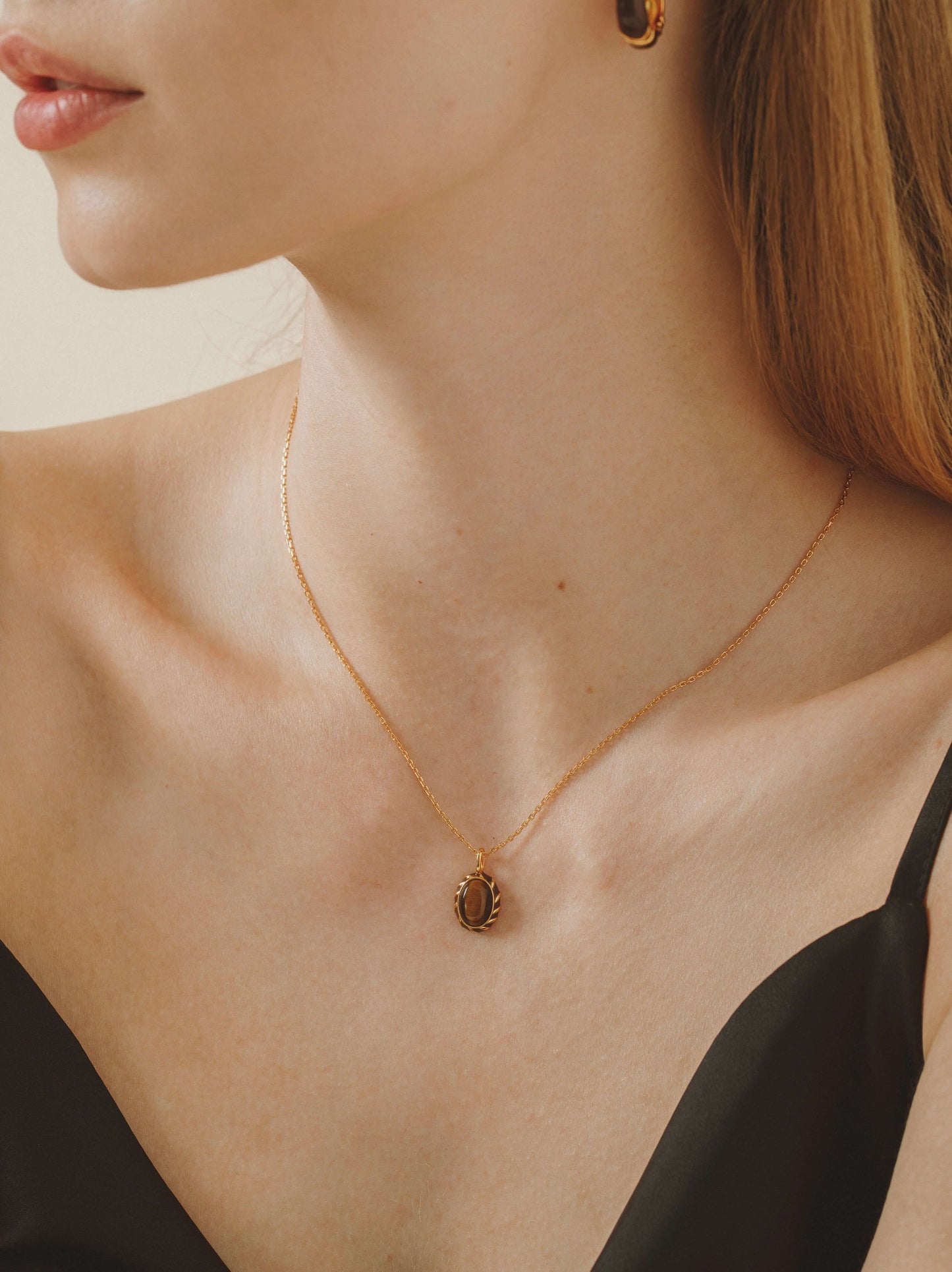 Elegant woman wearing SUIHE Jewelry "Mocha" Tiger Eye Stone Necklace with a gold vermeil chain and enamel pendant.