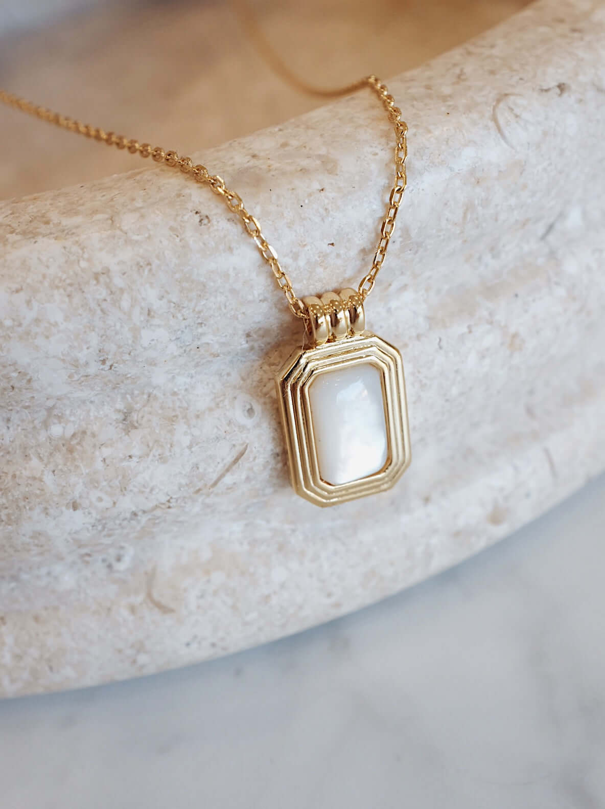SUIHE Jewelry Radiance necklace with mother-of-pearl in 18k gold vermeil, showcasing elegance and serenity on a textured surface.