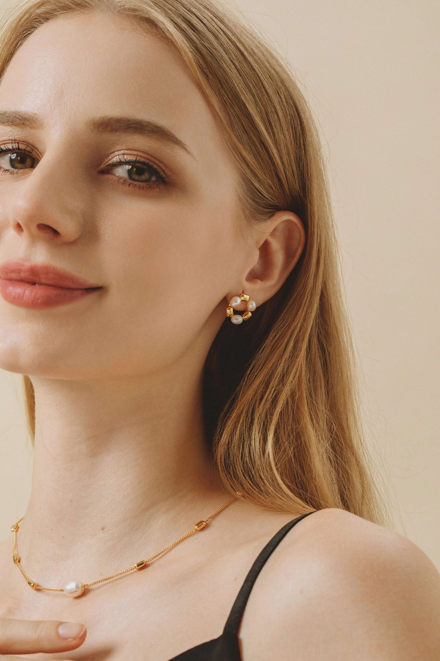 Woman wearing SUIHE Jewelry "Jellybean" freshwater pearl hoop earrings with 18k gold vermeil studs, highlighting chic elegance.