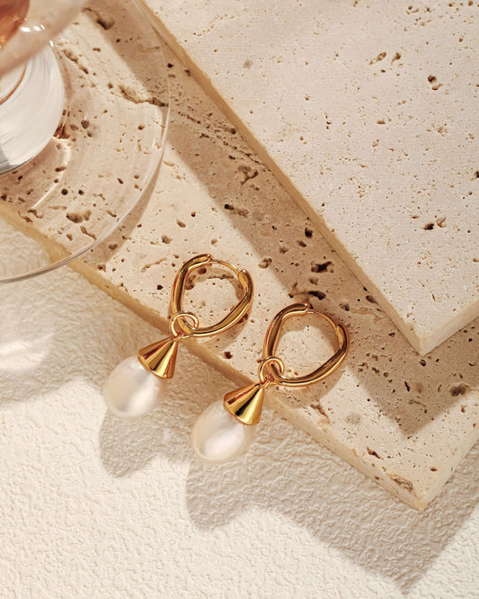 "Dewdrop" freshwater pearl earrings by SUIHE Jewelry on stone surface, featuring gold-plated silver and large, natural pearls.