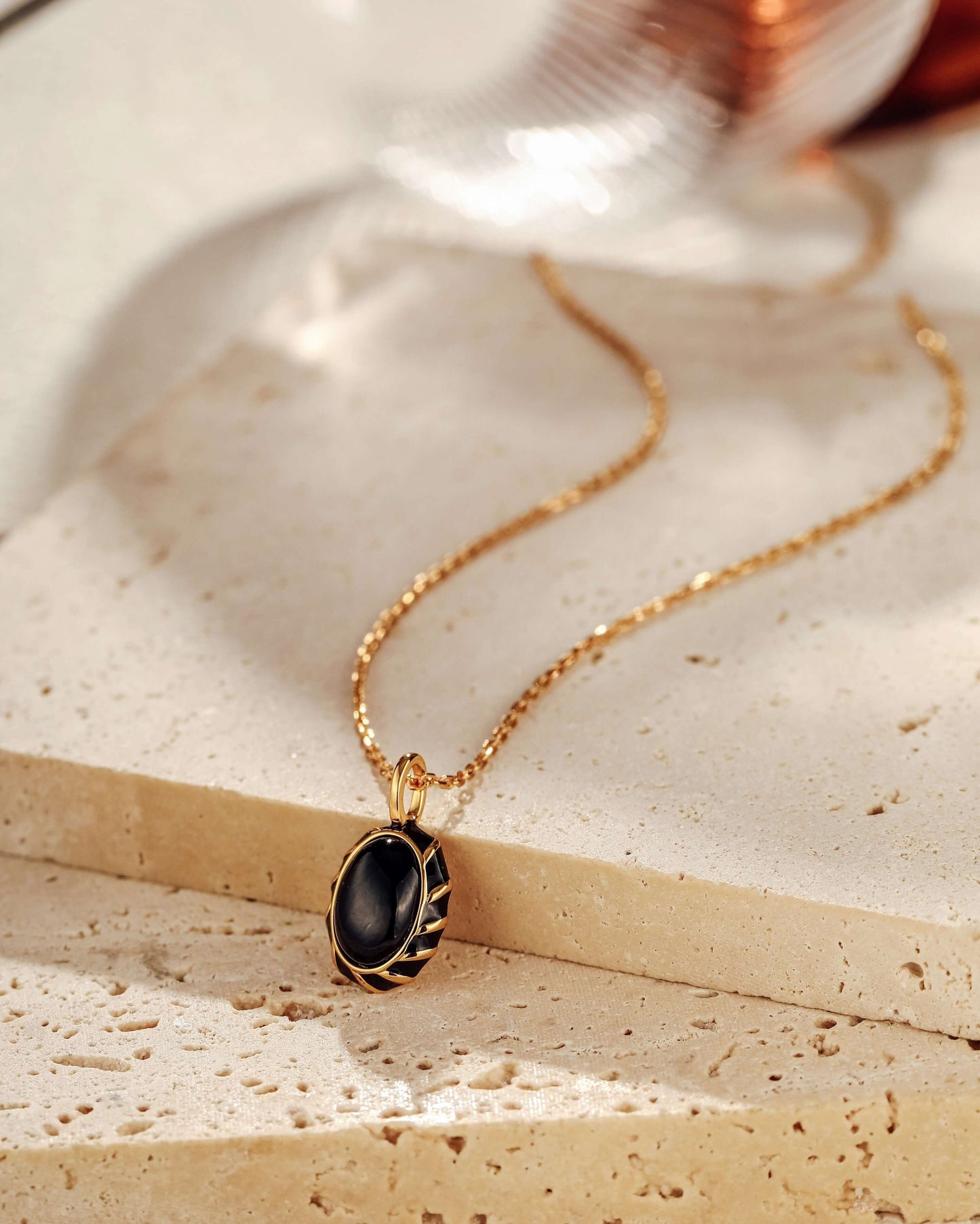 Eclipse black onyx and enamel necklace on gold chain by SUIHE Jewelry, displayed elegantly on a neutral background.