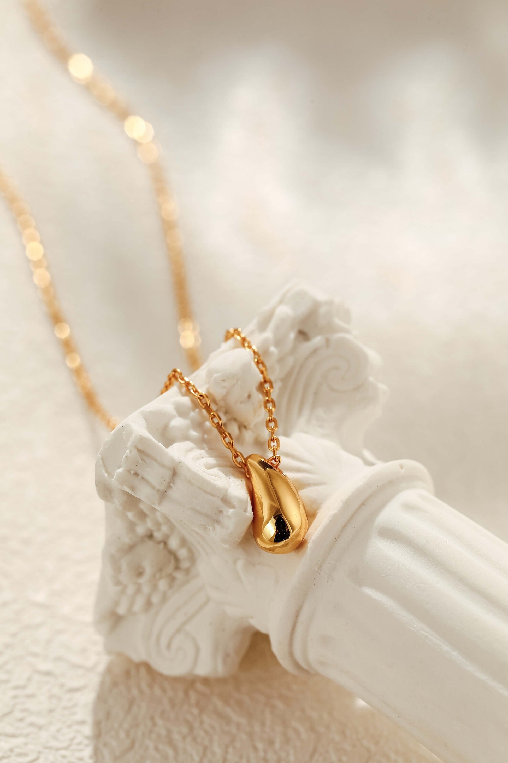 Teardrop Necklace in 18k Gold Vermeil by SUIHE Jewelry on a decorative white pedestal.