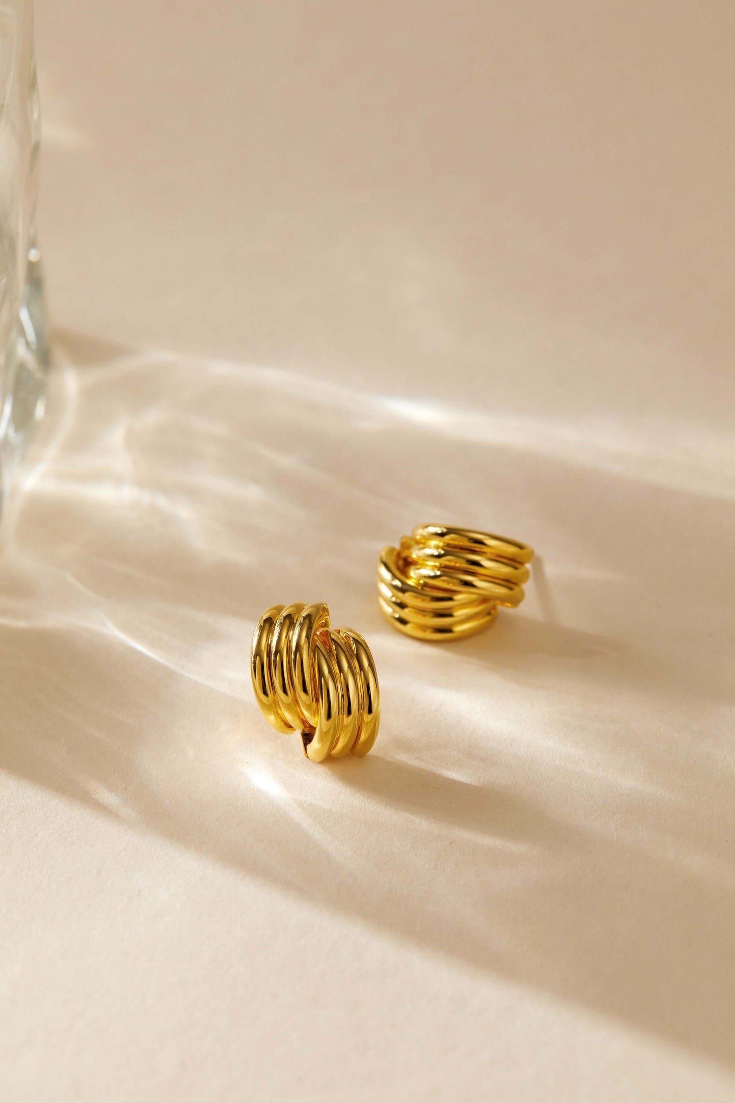 Gold-plated Wave Earrings by SUIHE Jewelry featuring sculptural curves and elegant design on a light background.