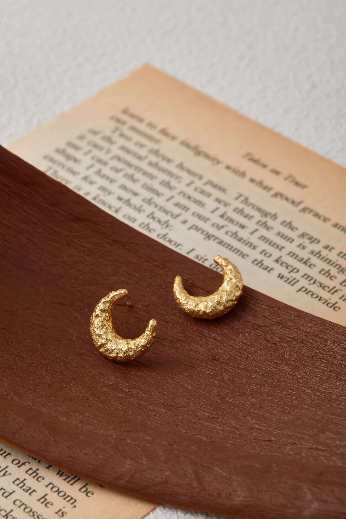 Gold-plated SUIHE Jewelry Moon Earrings with textured crescent design on a brown display, capturing the moon's beauty.