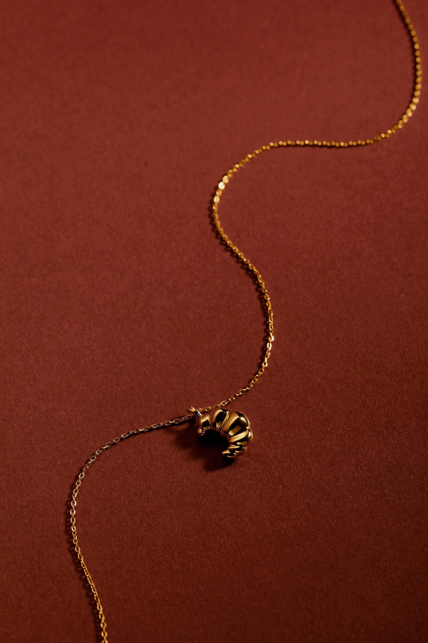 Gold "Croissant" Necklace by SUIHE Jewelry on a warm background, featuring textured charm inspired by Parisian elegance in 18k Gold Vermeil.