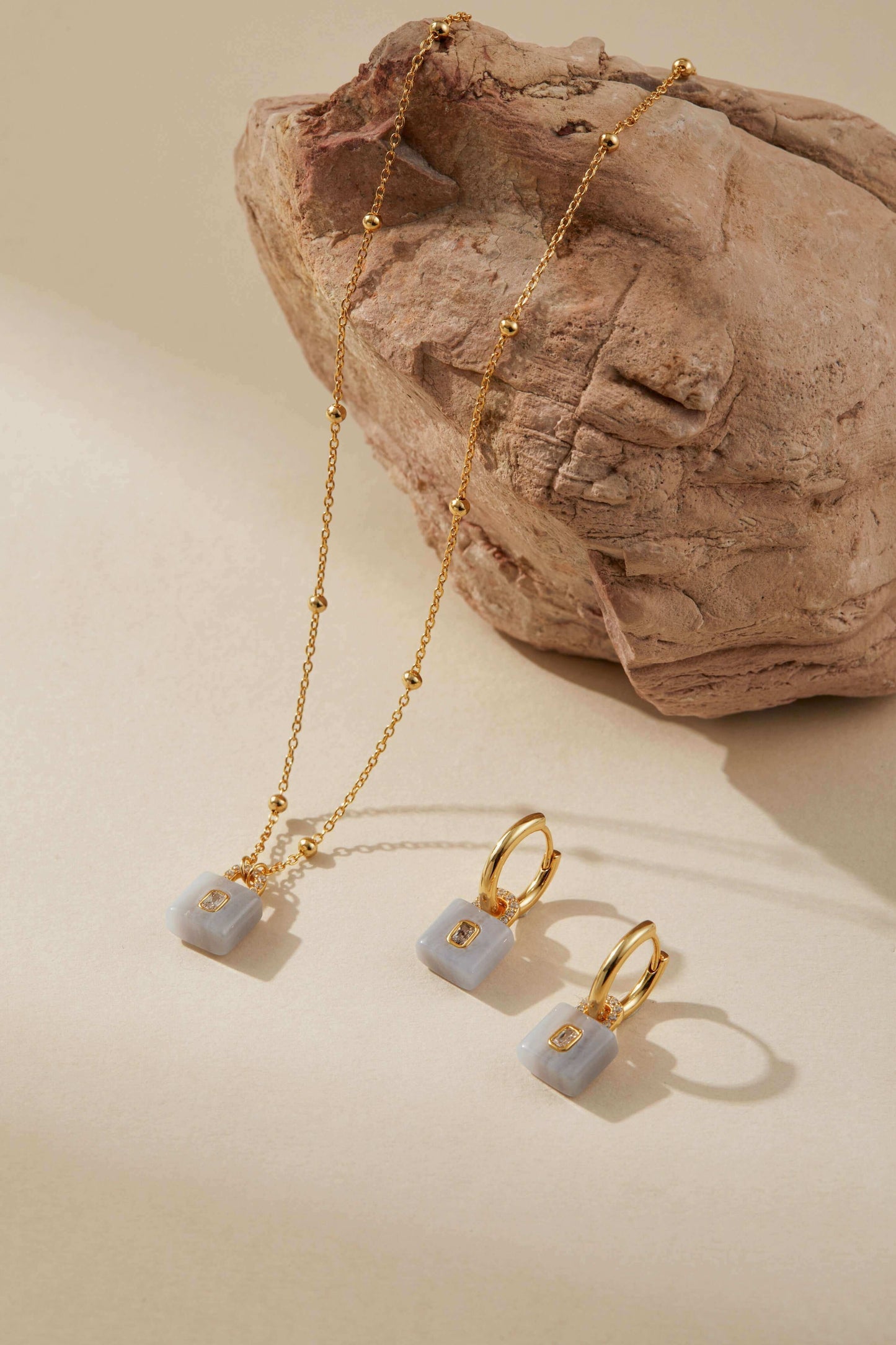 Gold-plated huggie hoops with aquamarine lock pendants by SUIHE Jewelry, highlighting polished stones for enhanced elegance.