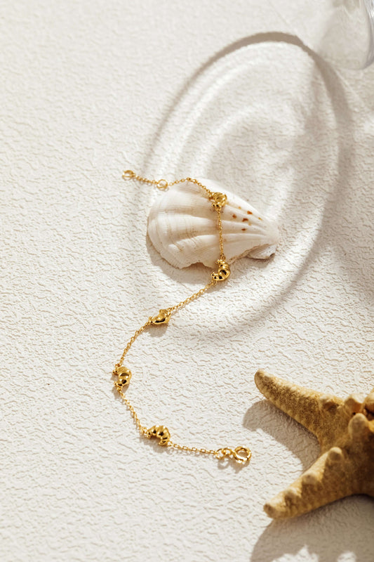 SUIHE Jewelry Croissant Mini Charm Bracelet with gold-plated chain and croissant charms on seashell background.