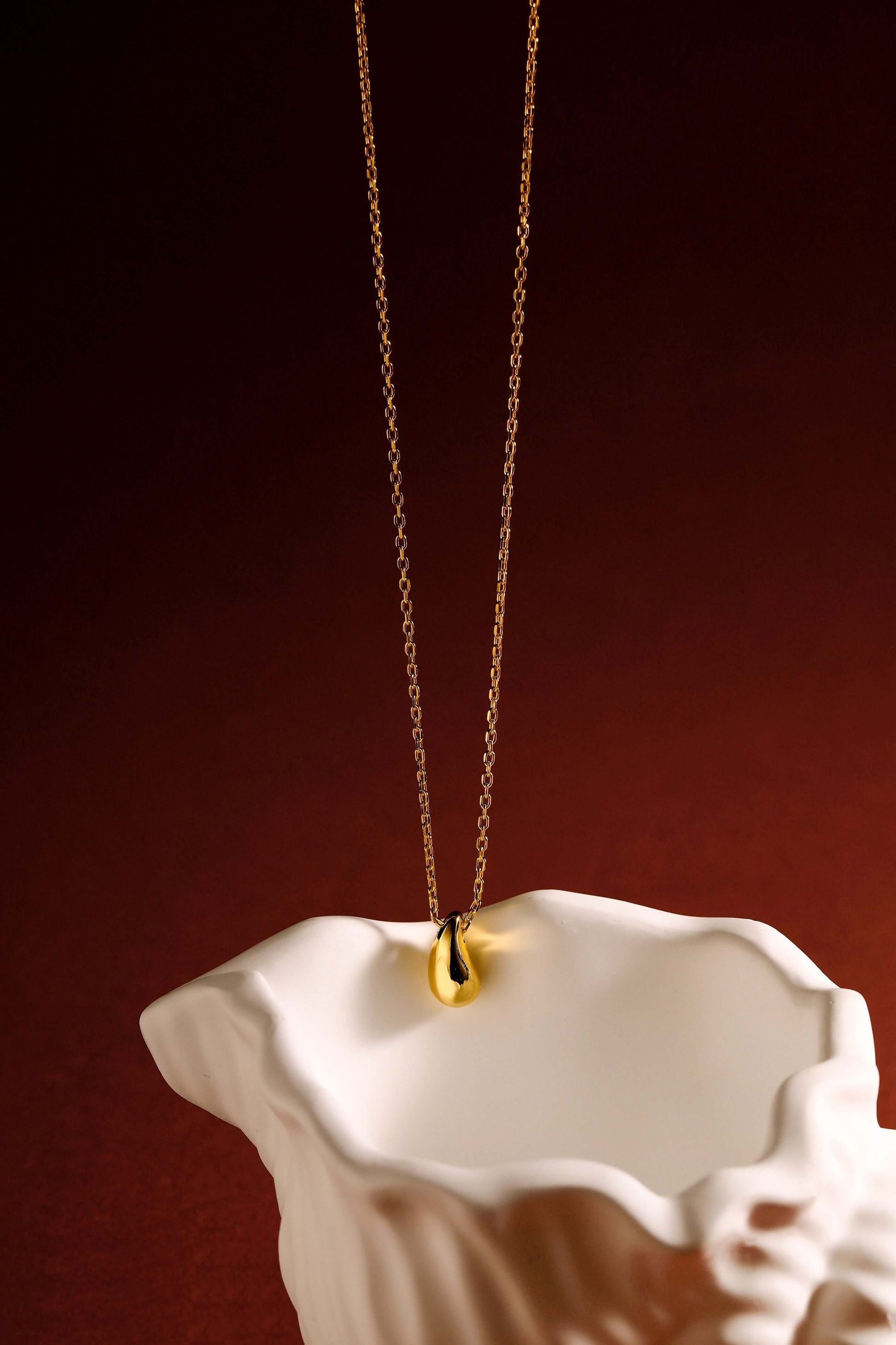 "Teardrop" Necklace by SUIHE Jewelry in 18k Gold Vermeil, symbolizing resilience and beauty, elegantly displayed on a ceramic backdrop.