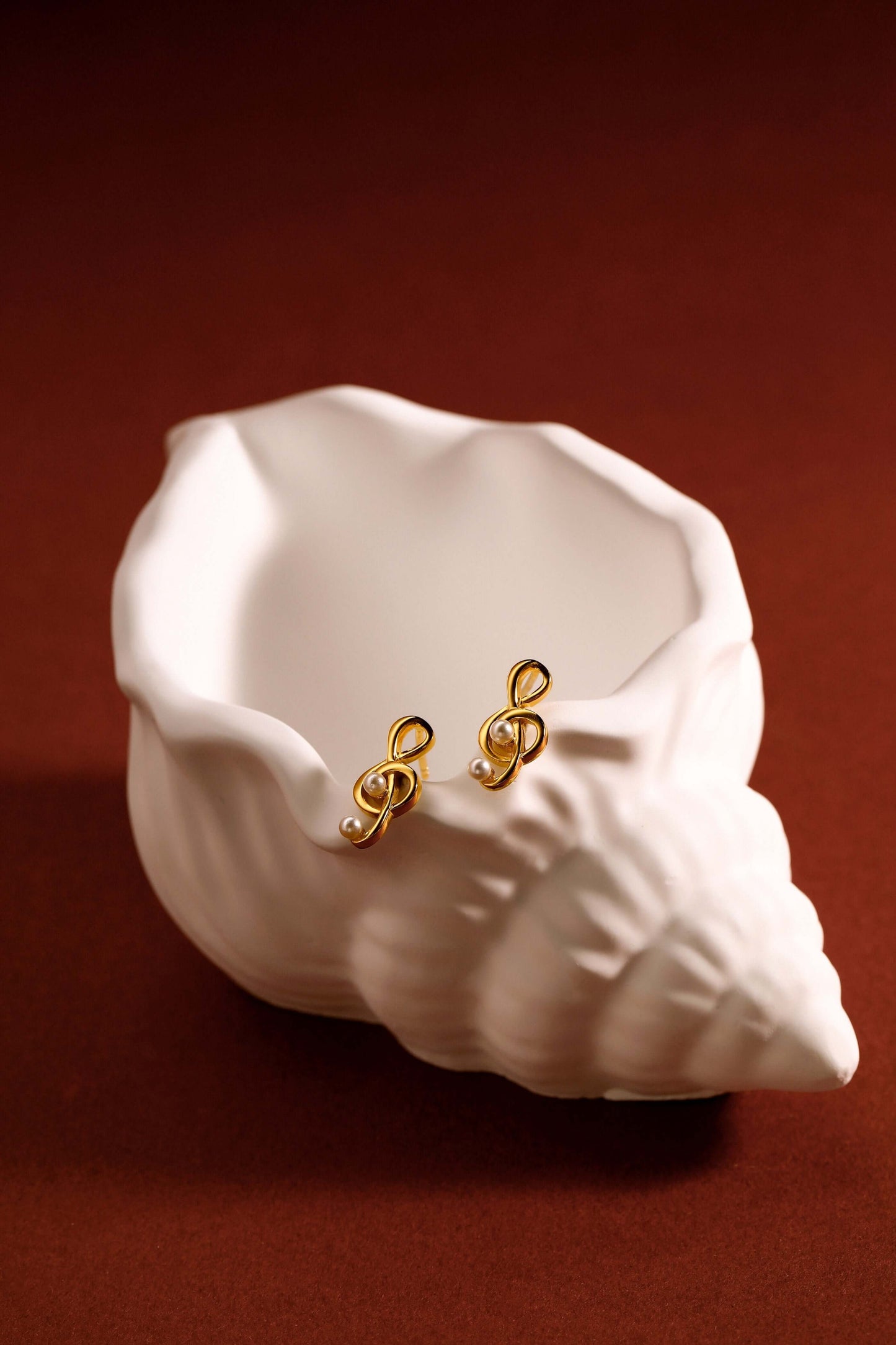 Aria stud earrings in 18k gold vermeil over sterling silver by SUIHE Jewelry displayed on a white decorative shell.