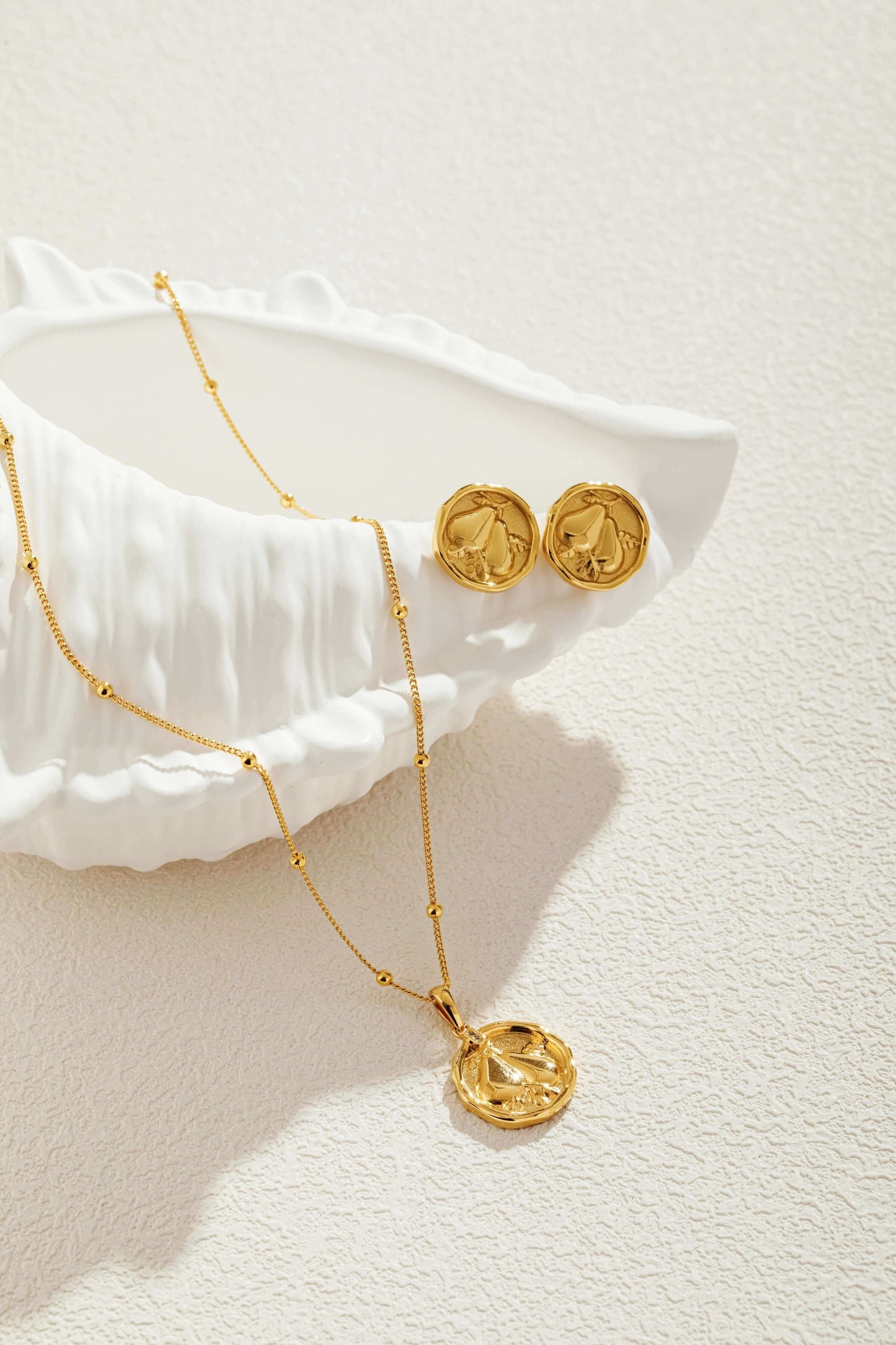 18K gold Pear necklace with bead accents from SUIHE Jewelry displayed with matching earrings on a textured surface.