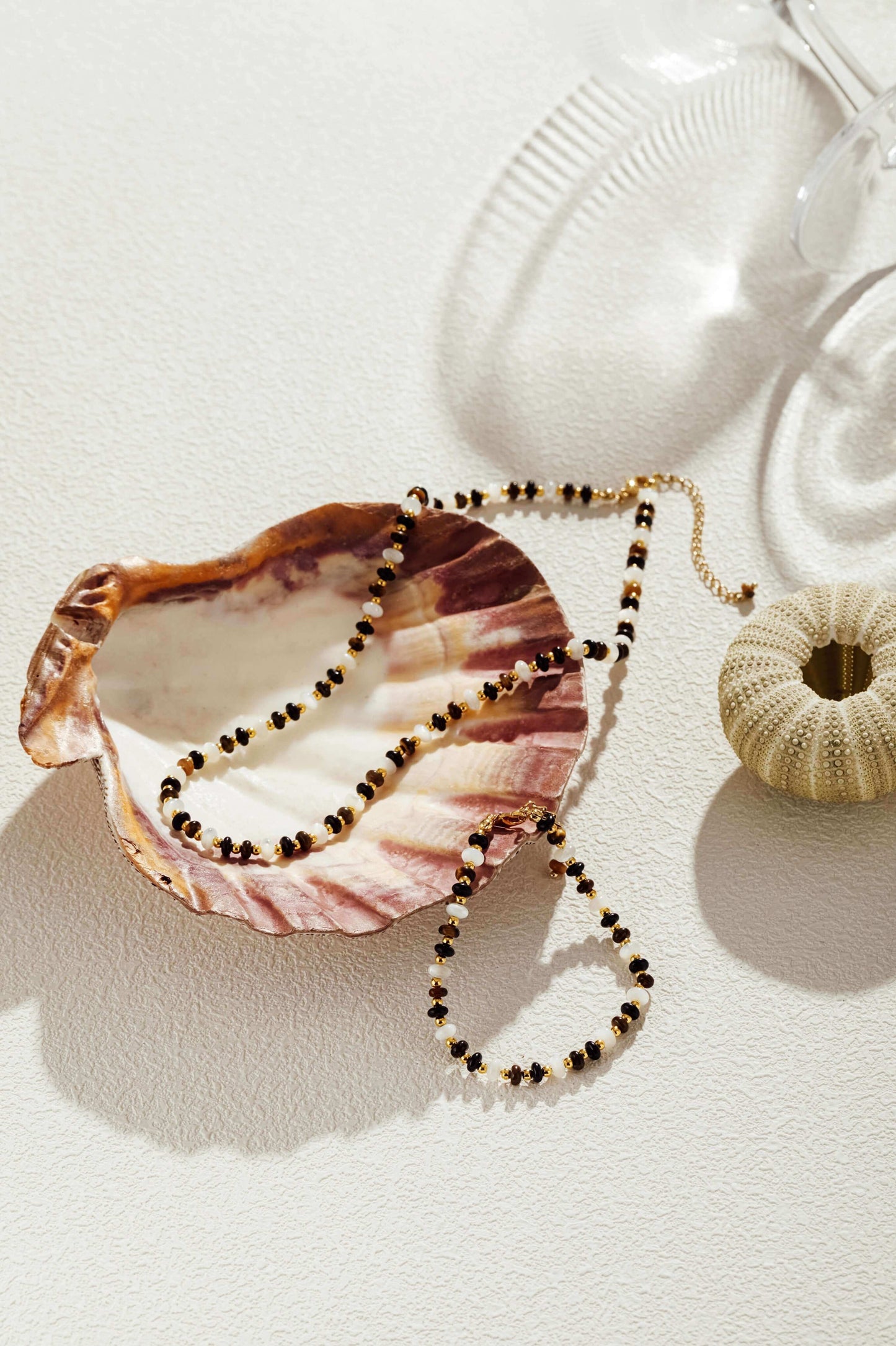 Elegant SUIHE Jewelry natural gemstone necklace with marbled beads and pearls, gold-tone accents displayed in a seashell for sophistication.