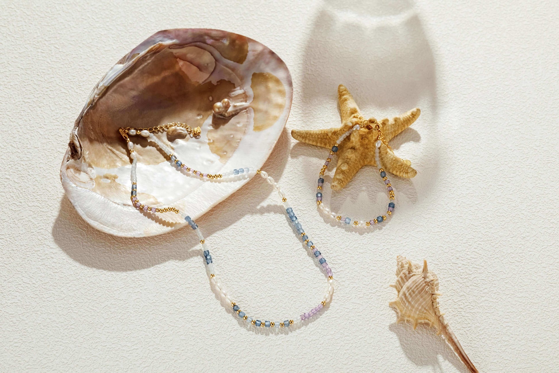 Ocean Natural Gemstone Necklace by SUIHE Jewelry displayed with seashell and starfish, featuring pearls and blue, lavender gemstones.