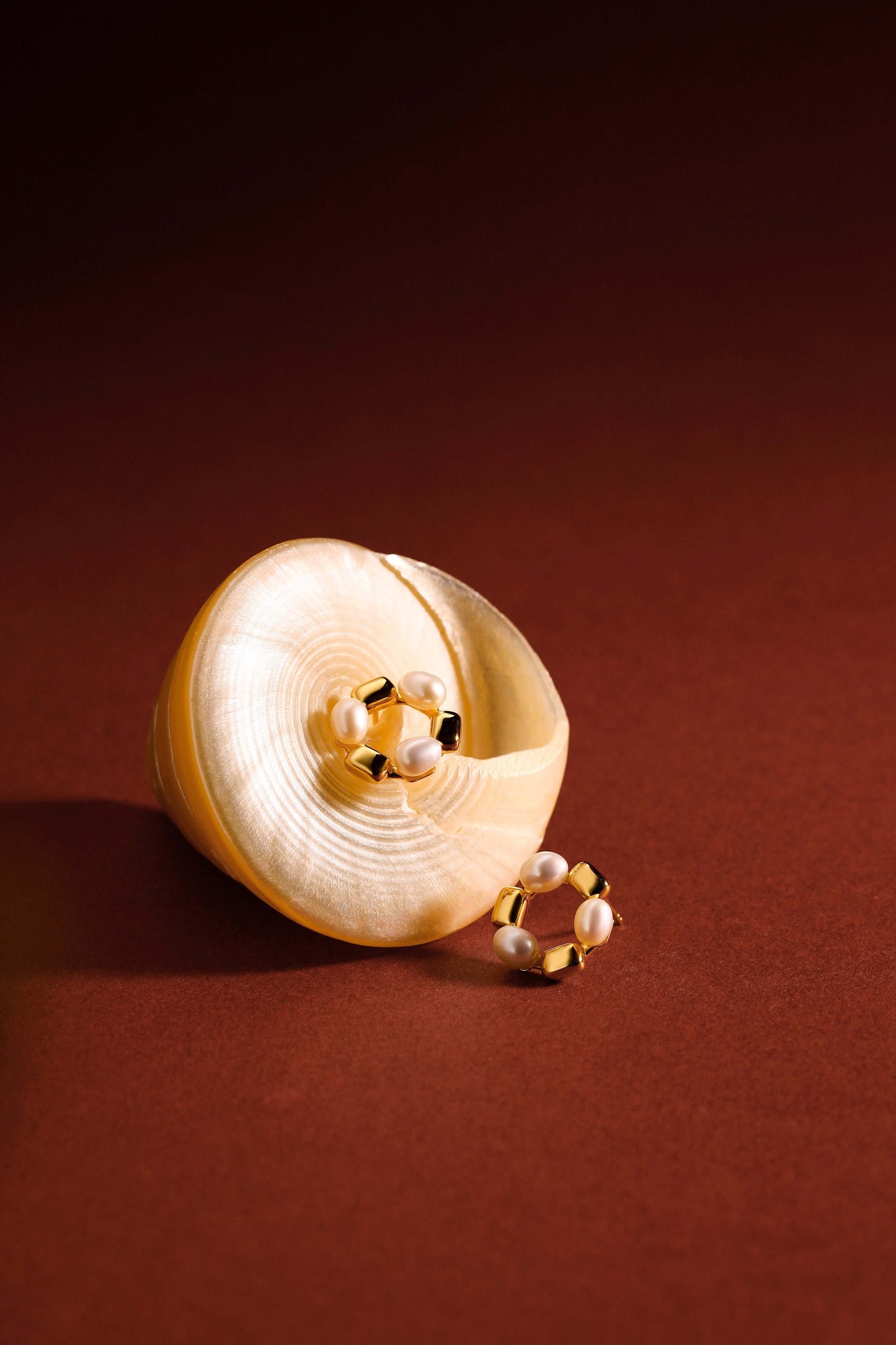 SUIHE Jewelry "Jellybean" freshwater pearl hoop earrings with 18k gold vermeil and copper on a shell backdrop.