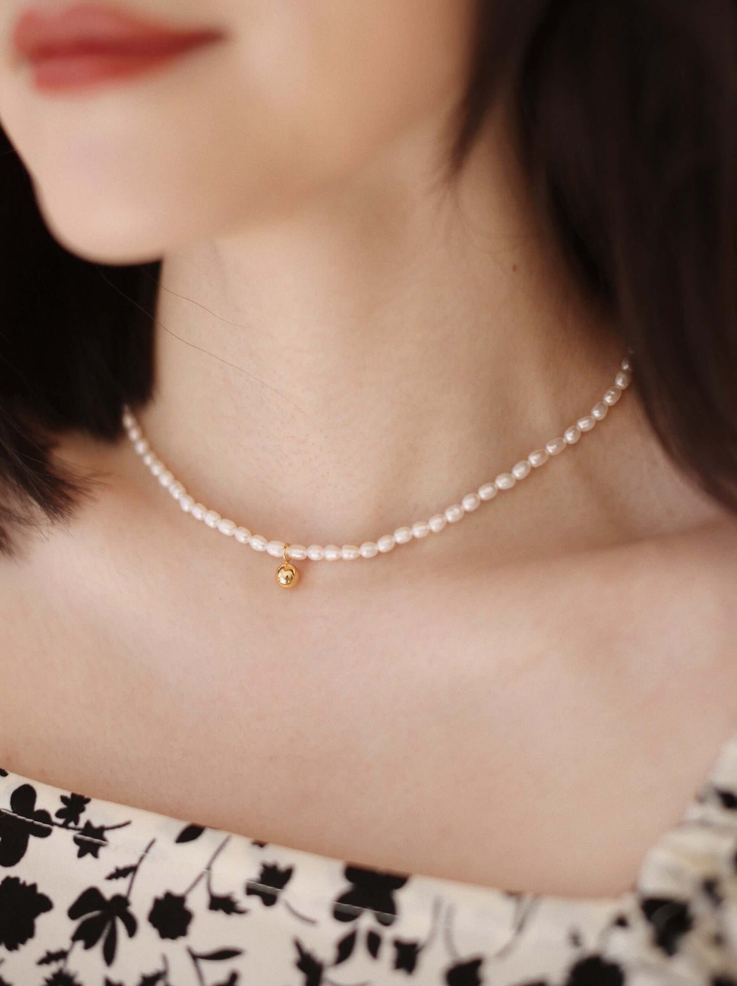 Woman wearing Celestia Freshwater Pearl Necklace by SUIHE Jewelry, featuring 3-4mm pearls and 18k gold vermeil pendant, close-up view.