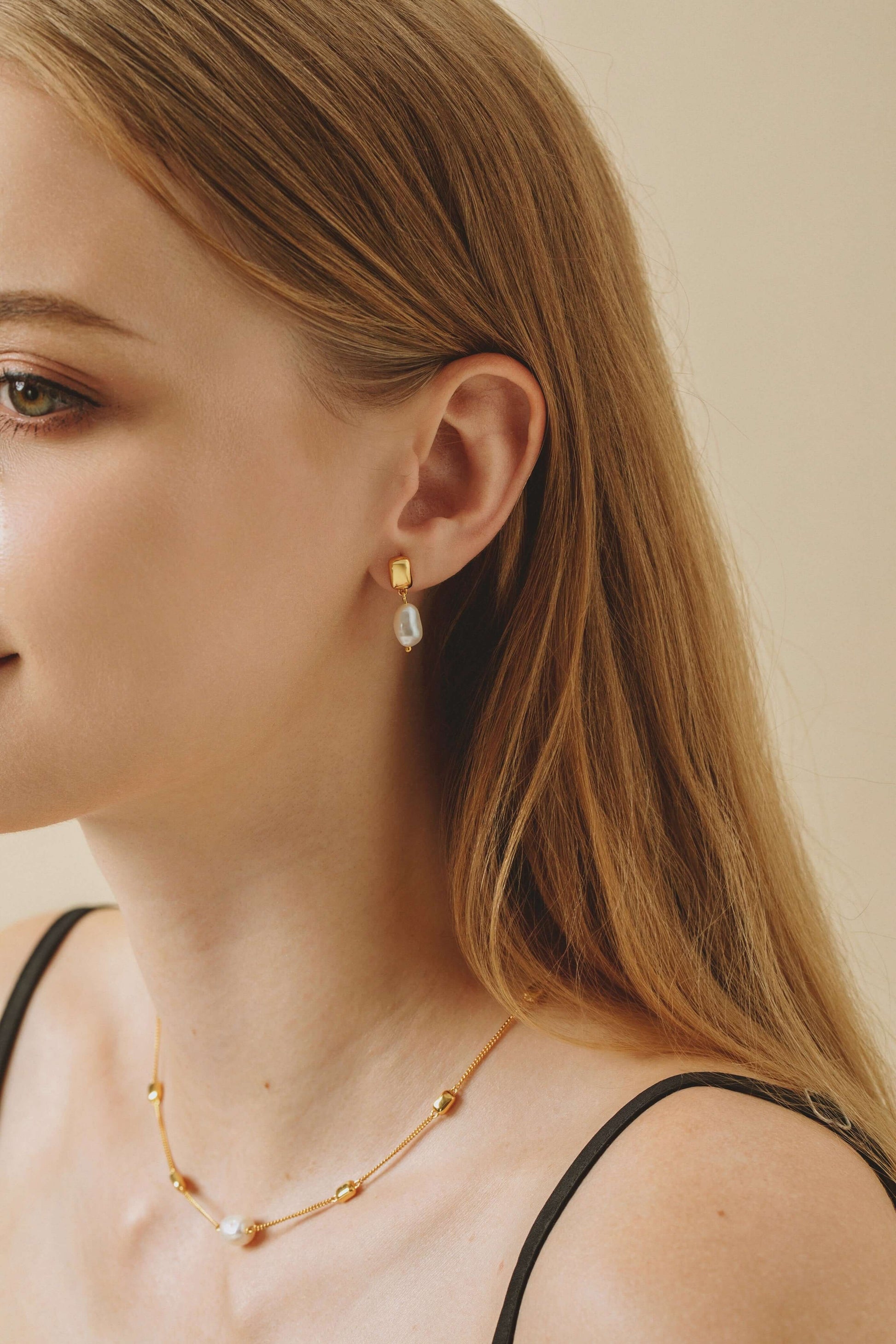 Woman wearing SUIHE Jewelry Jellybean Baroque Pearl Earrings in 18k gold vermeil, showcasing elegance and contemporary style.