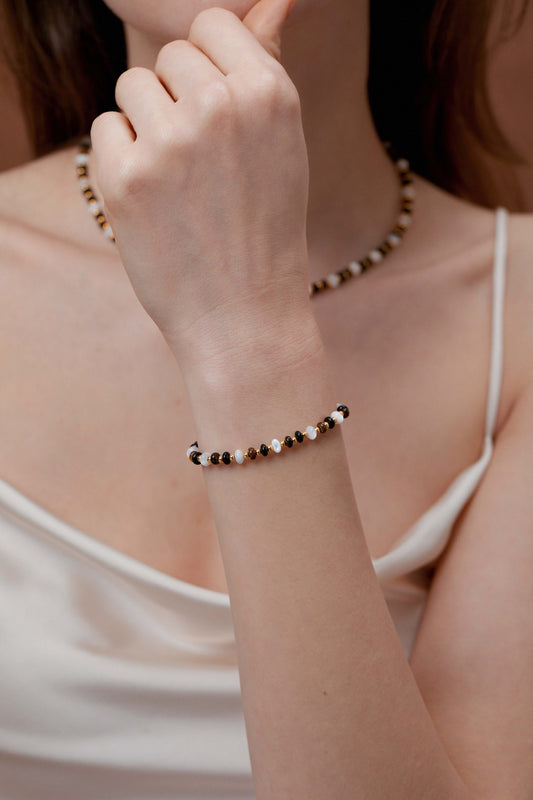 Close-up of a woman wearing a SUIHE Jewelry Marble Natural Gemstone Bracelet with marbled beads and gold-tone accents, matched with a necklace.