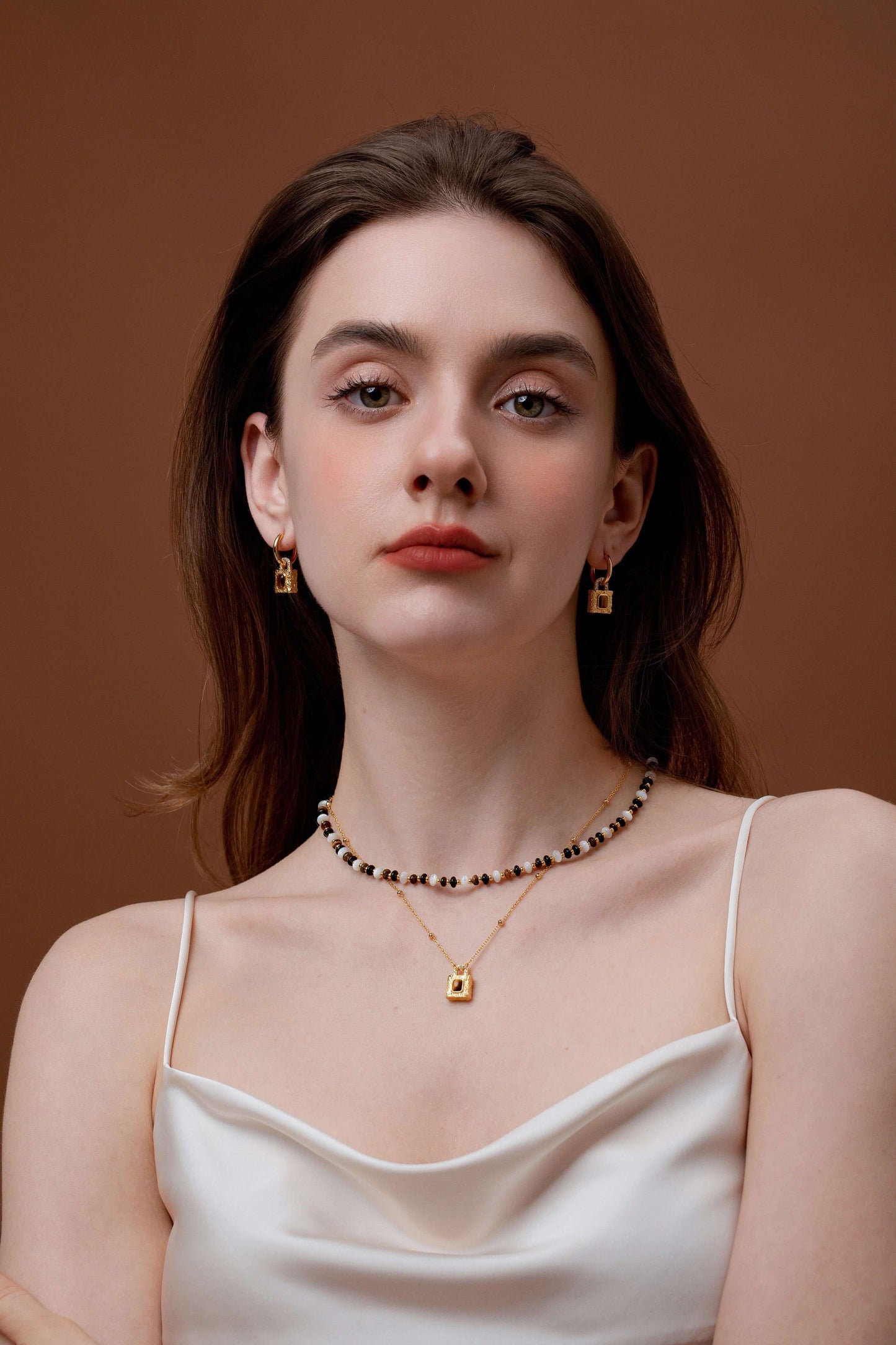 Woman wearing SUIHE Jewelry Lock Tiger Eye Stone Necklace with gold lock pendant and earrings, exuding elegance and confidence.