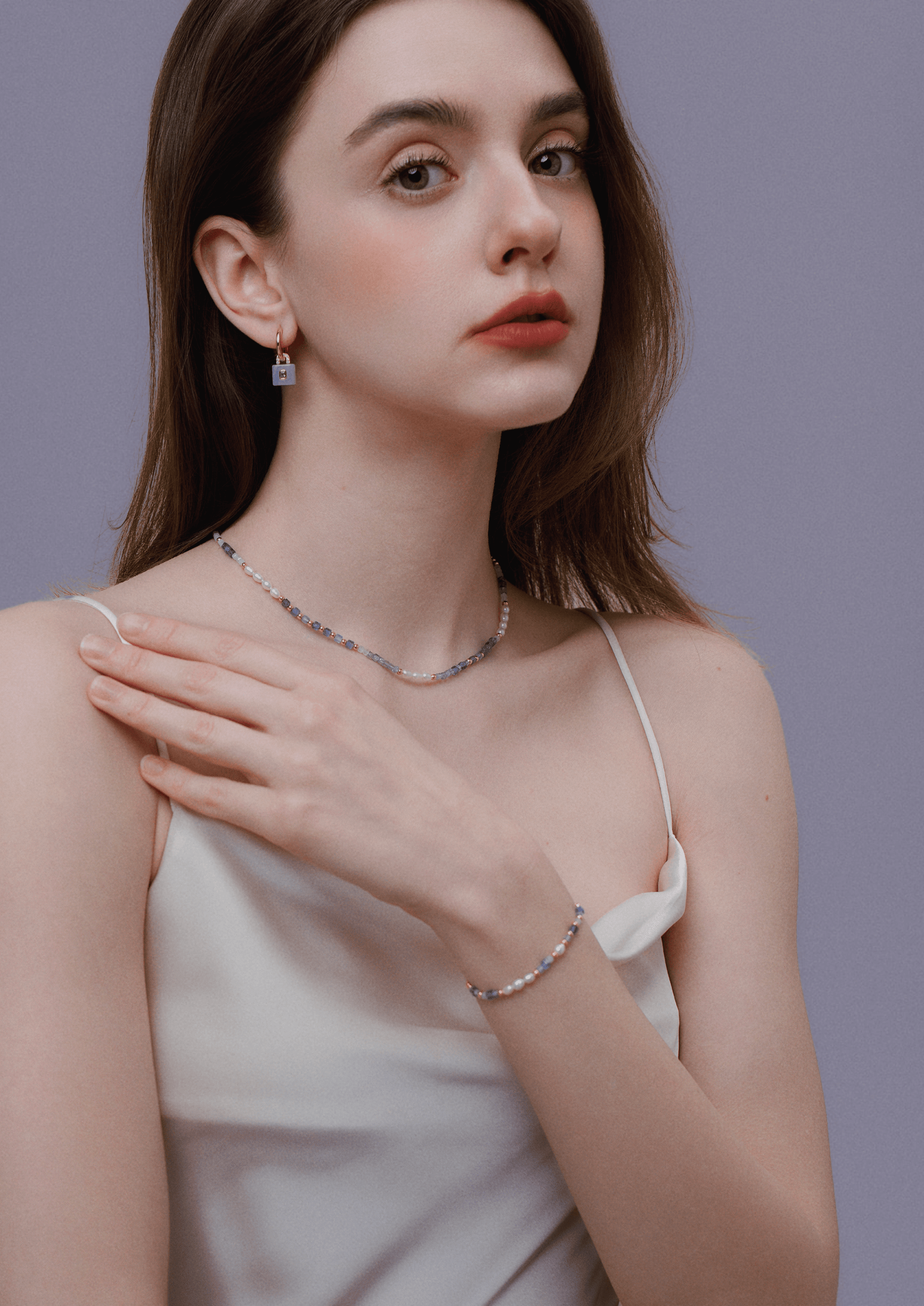 Woman wearing "Ocean" Natural Gemstone Necklace by SUIHE Jewelry, featuring blue, lavender, and white gemstones with gold-plated beads.