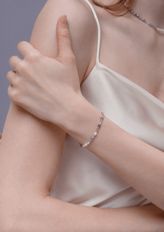 Woman wearing Ocean Natural Gemstone Bracelet by SUIHE Jewelry, featuring blue, lavender, and white gemstones with gold accents.