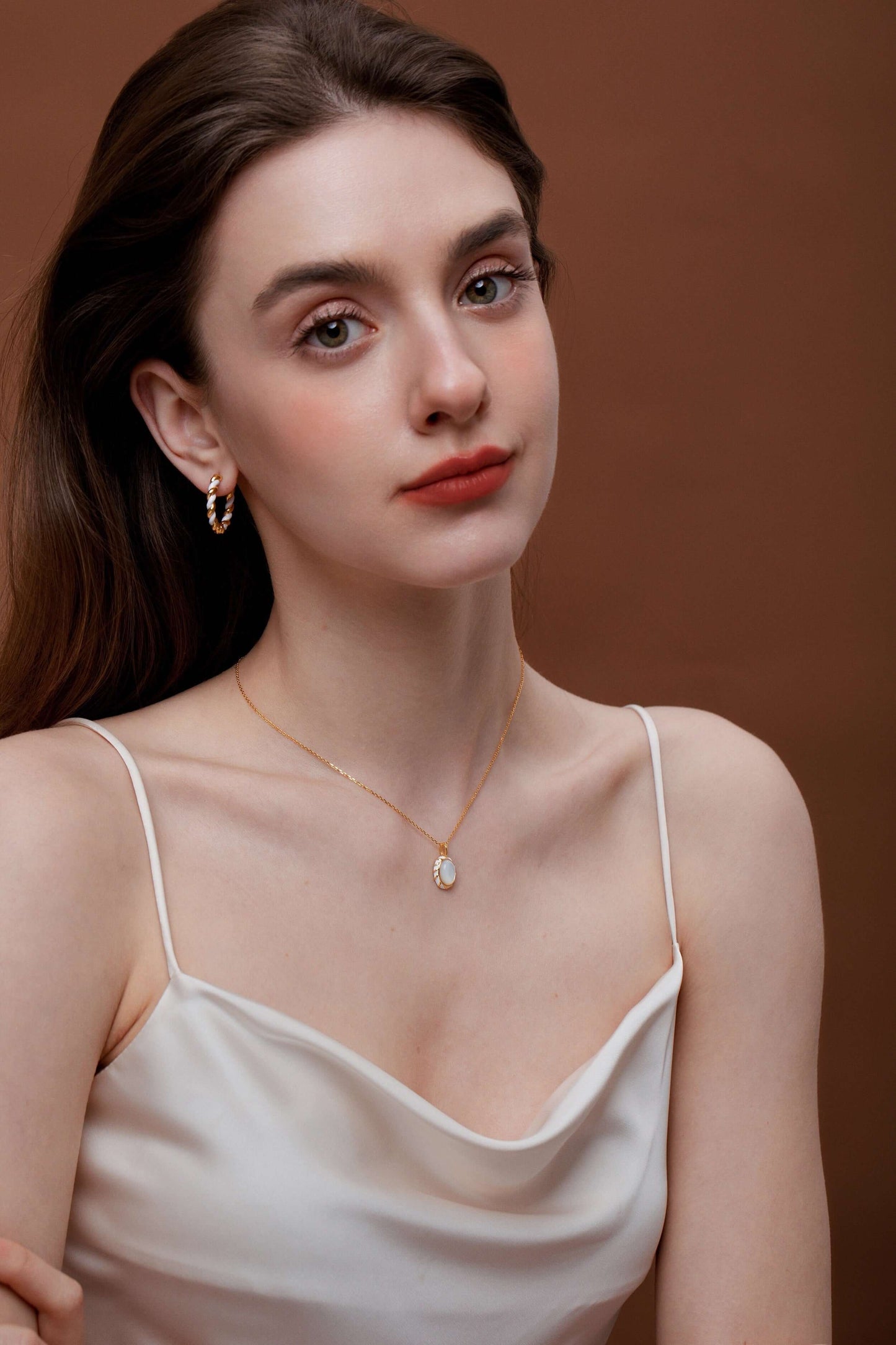Woman wearing SUIHE Jewelry Dough Twist Hoop Earrings and necklace, elegant style with a white top against a brown background.