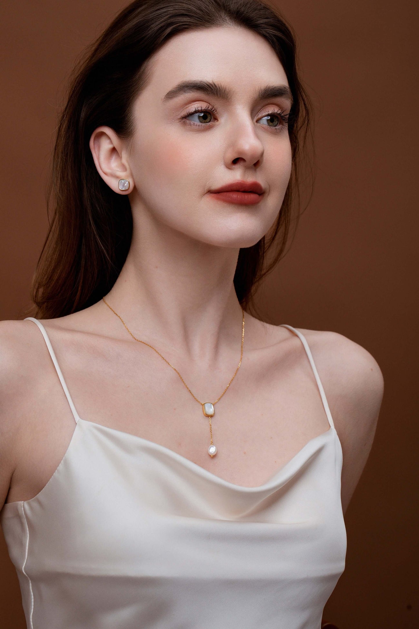 Woman wearing SUIHE Jewelry Allure Mother-Of-Pearl with Pearl Drop Necklace featuring elegant modern design on a silky white dress.