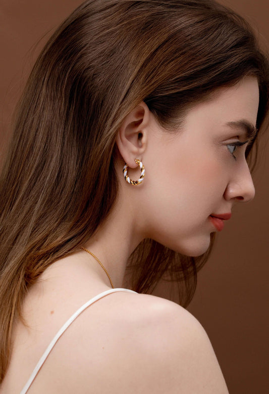 Woman wearing SUIHE Jewelry Dough Twist Hoop Earrings in polished 18K gold and white enamel with a sophisticated intertwined design.