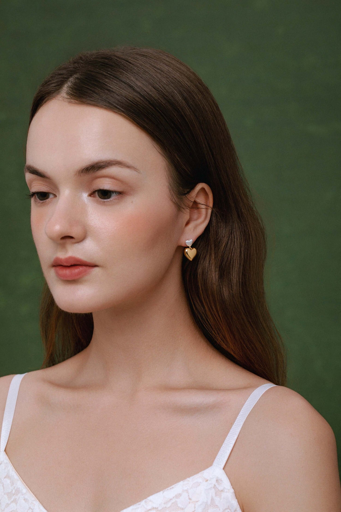 Model wearing Amour Double Heart Earrings by SUIHE Jewelry, featuring brushed silver and polished gold hearts for a sophisticated look.