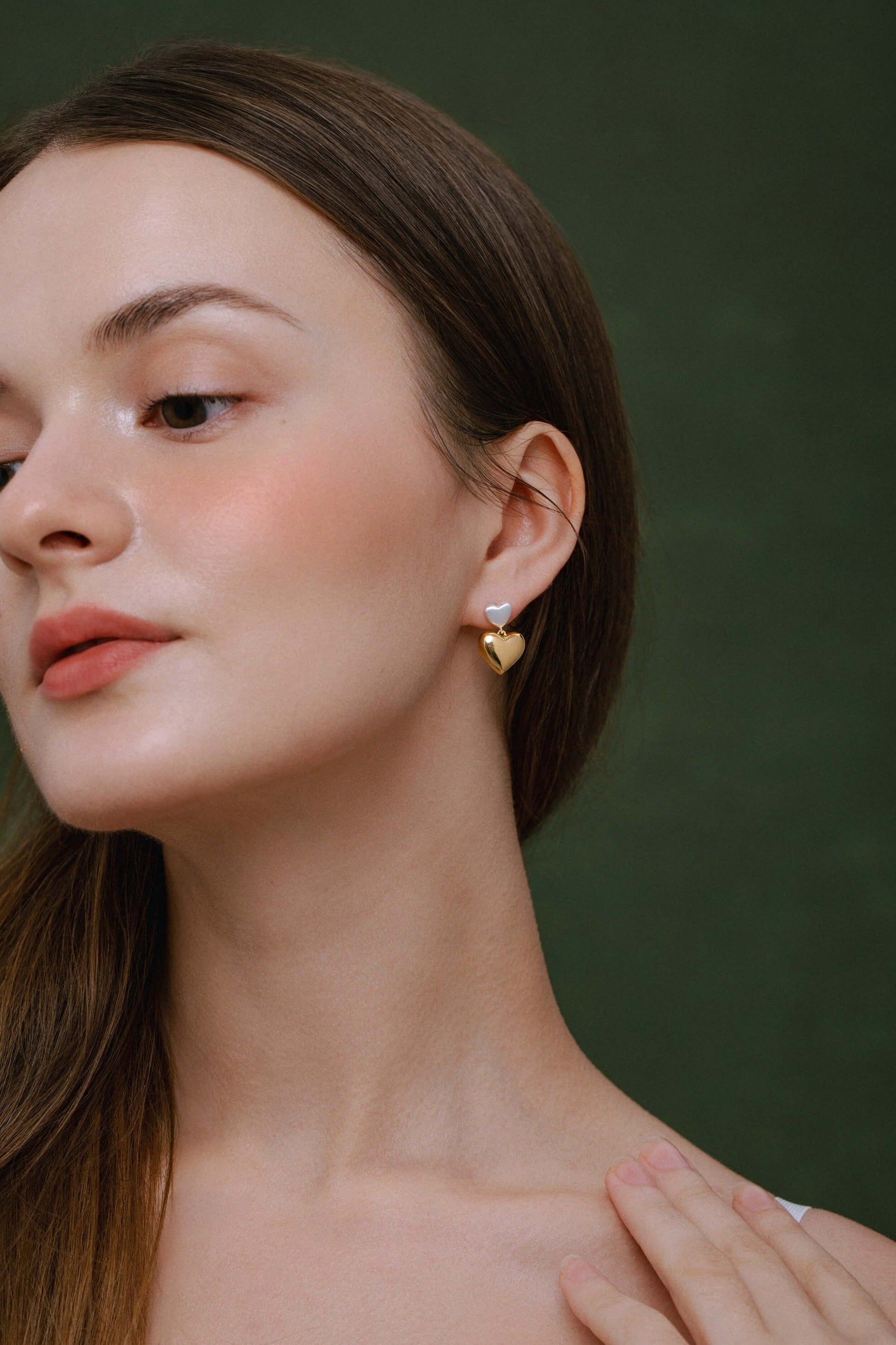 Woman wearing Amour Double Heart Earrings by SUIHE Jewelry, featuring silver and gold hearts, showcasing love and elegance.