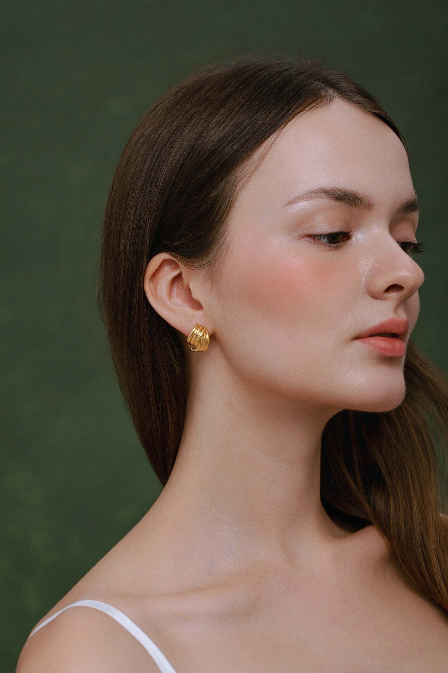 Close-up of woman wearing gold-plated SUIHE Jewelry Wave Earrings against a green background, showcasing modern elegance and sophistication.