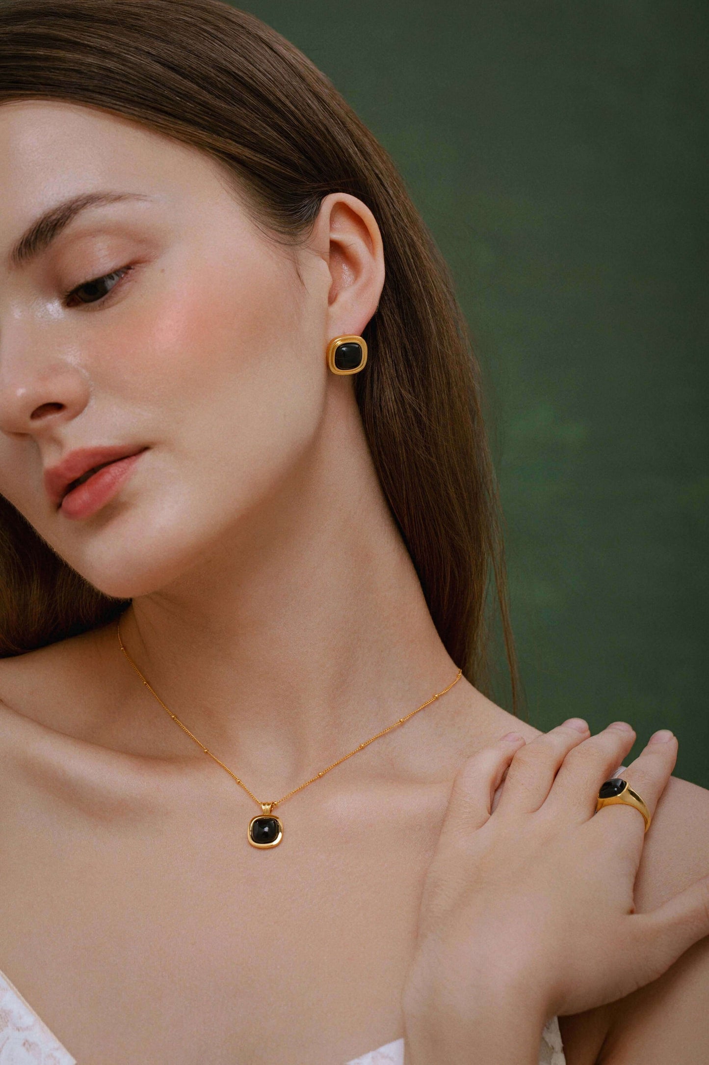Model wearing SUIHE Jewelry "Nocturne" Black Onyx Square Necklace with matching earrings and ring against a green background.