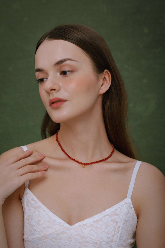 Woman wearing a Lucky Red Agate Gemstone Necklace by SUIHE Jewelry, featuring vibrant red stones on 18k gold vermeil.