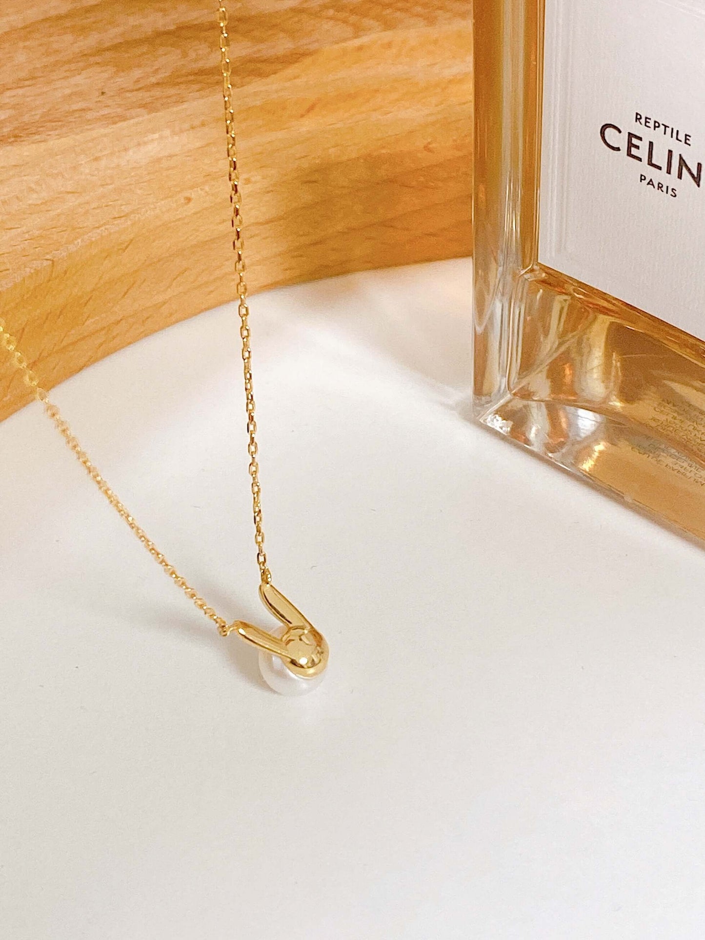 SUIHE Jewelry Bunny Freshwater Pearl Necklace with 18k Gold Vermeil chain displayed elegantly beside a decorative bottle.