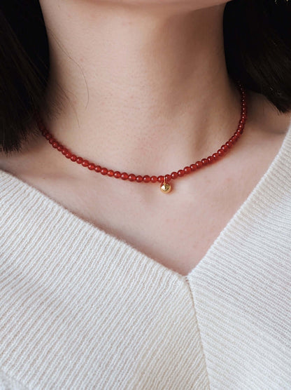 Close-up of a model wearing the "Lucky" Red Agate Gemstone Necklace by SUIHE Jewelry, featuring vibrant red agate with gold vermeil.