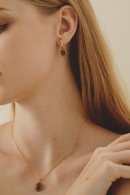 Model wearing SUIHE Jewelry 'Mocha' pendant earrings crafted in 18k gold-plated silver with tiger's eye stones and yellow enamel.