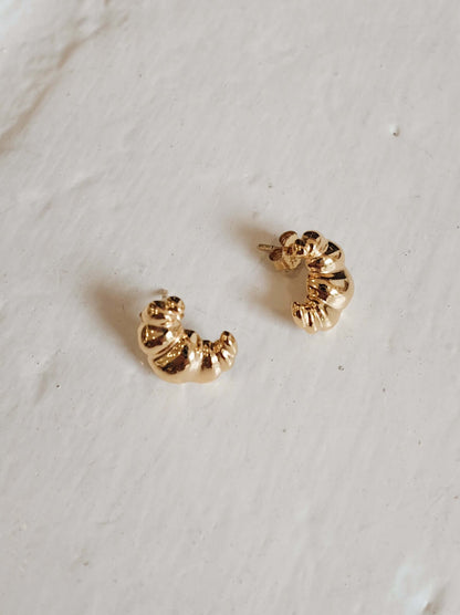 Elegant 18k gold vermeil Croissant Stud Earrings by SUIHE Jewelry, inspired by Parisian charm, set on a textured surface.