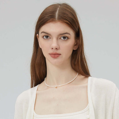 Woman wearing Celestia freshwater pearl necklace with 18k gold vermeil by SUIHE Jewelry, featuring 3-4mm pearls, 16" chain with extender.
