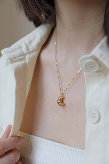 Woman wearing SUIHE Jewelry Croissant Necklace in 18k Gold Vermeil resembling a croissant, styled elegantly with a casual shirt.