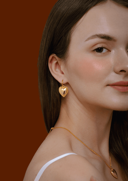 Woman wearing SUIHE Jewelry 'Adore' Heart Charm Hoop Earrings in gold, showcasing elegant design with beaded detailing.