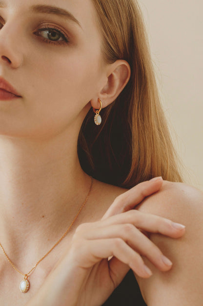 Woman wearing SUIHE Jewelry's "Luna" mother-of-pearl pendant earrings in 18k gold vermeil.