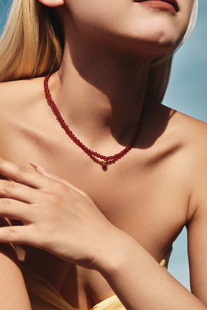 Woman wearing SUIHE Jewelry 'Lucky' red agate gemstone necklace with 18k gold vermeil chain, symbolizing elegance and good fortune.