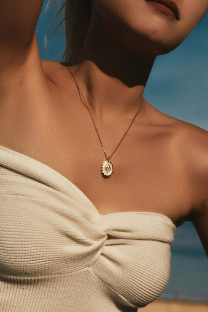 Woman wearing golden tulip necklace, SUIHE Jewelry, in elegant off-shoulder top against a blue sky background.