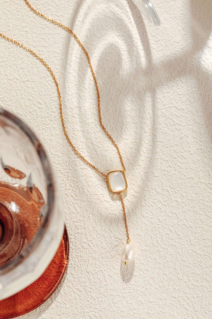 Allure Mother-Of-Pearl and Pearl Drop Necklace by SUIHE Jewelry displayed on textured surface