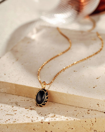 Eclipse black onyx and enamel necklace on gold chain by SUIHE Jewelry, displayed elegantly on a neutral background.