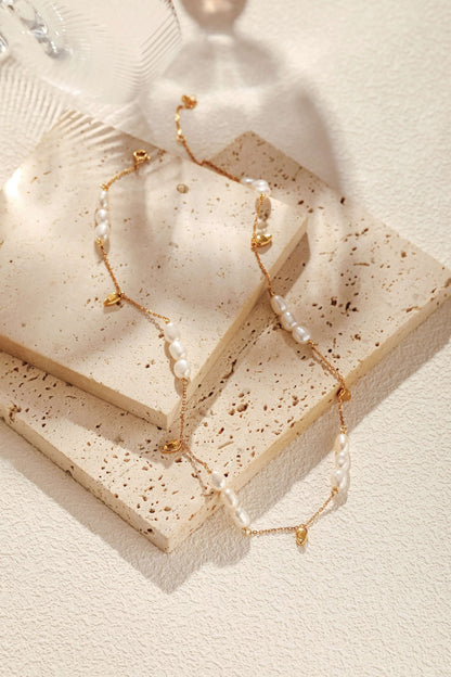 "Candybean" Pearl Necklace with irregular-shaped pearls on gold-plated chain by SUIHE Jewelry, displayed on stone surface.