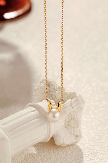 Bunny Freshwater Pearl Necklace on 18k Gold Vermeil chain, SUIHE Jewelry, showcasing elegance and whimsy on a decorative pillar.