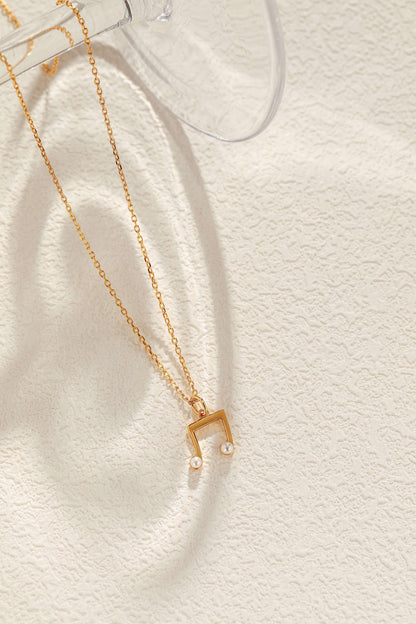 "Melody" necklace by SUIHE Jewelry in 18k gold vermeil with freshwater pearls on a textured background.