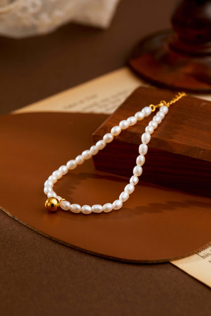 Celestia freshwater pearl bracelet by SUIHE Jewelry with gold-tone bead charm on brown background, elegant and adjustable.